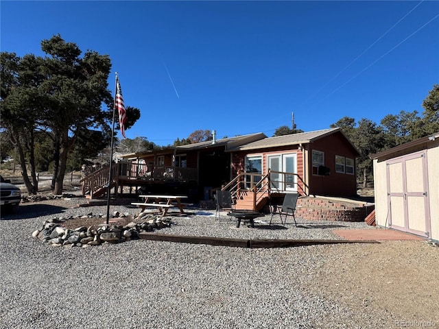 back of house with a wooden deck and a storage shed