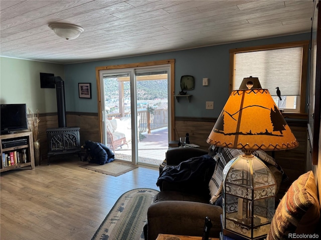 living room with wood ceiling, wooden walls, hardwood / wood-style floors, and a wood stove