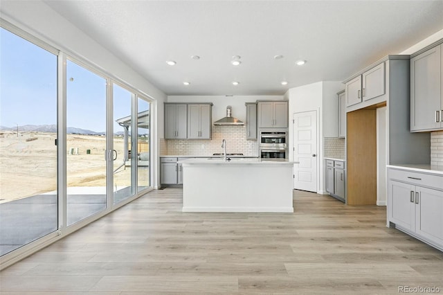kitchen featuring recessed lighting, wall chimney exhaust hood, decorative backsplash, and gray cabinetry