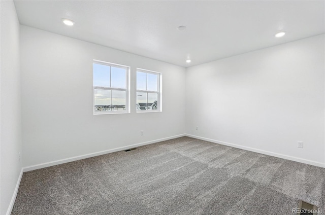carpeted empty room featuring baseboards, visible vents, and recessed lighting