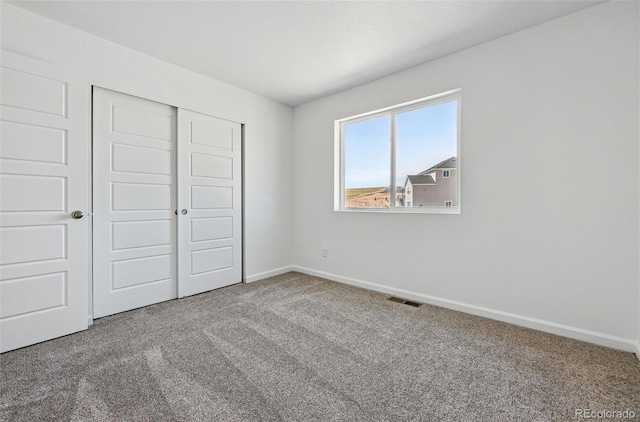 unfurnished bedroom featuring baseboards, carpet floors, visible vents, and a closet