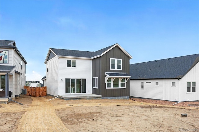 back of house with board and batten siding, fence, and cooling unit