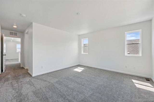 carpeted empty room featuring visible vents and a healthy amount of sunlight