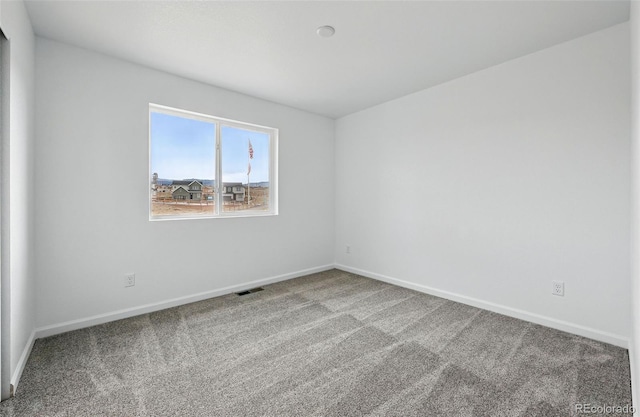 spare room featuring baseboards, visible vents, and carpet