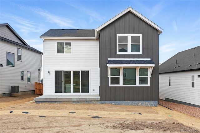 back of property featuring board and batten siding, roof with shingles, central air condition unit, and a patio