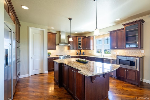 27565 E Nova Pl, Aurora, CO 80016 - kitchen featuring wall chimney exhaust hood, built in appliances, dark wood-style flooring, a center island, and recessed lighting