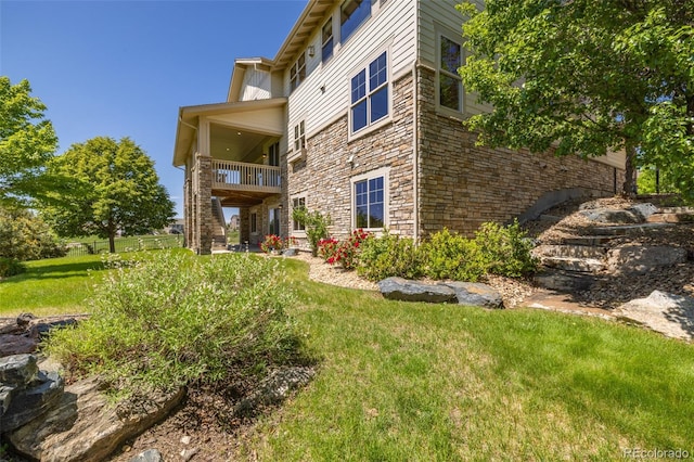 27565 E Nova Pl, Aurora, CO 80016 - rear view of house featuring stone siding, a balcony, and a yard