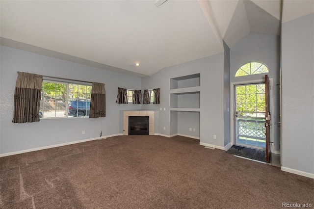 unfurnished living room with built in features, baseboards, dark carpet, a tile fireplace, and high vaulted ceiling