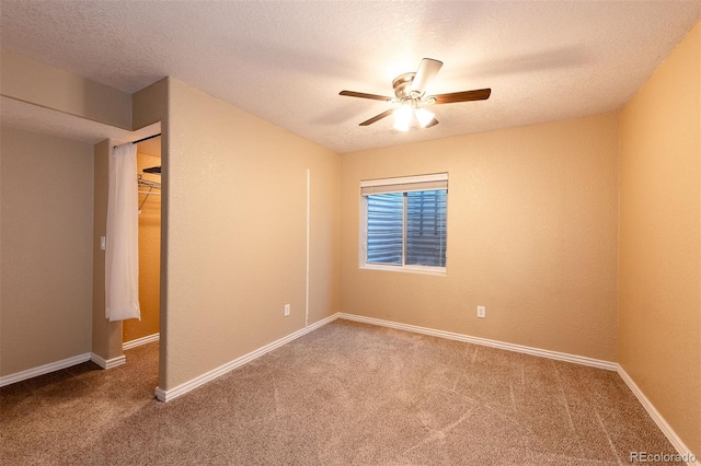 carpeted empty room with a ceiling fan, a textured ceiling, and baseboards