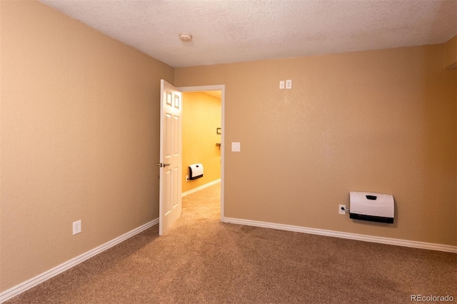 unfurnished room with a textured ceiling, carpet floors, a smoke detector, heating unit, and baseboards