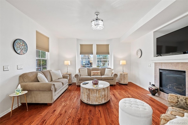 living room featuring a tiled fireplace, plenty of natural light, and hardwood / wood-style floors