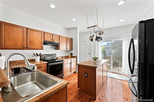 kitchen with a center island, electric stove, sink, hardwood / wood-style flooring, and fridge