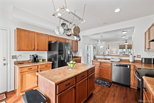 kitchen featuring appliances with stainless steel finishes, a center island, dark wood-type flooring, and sink