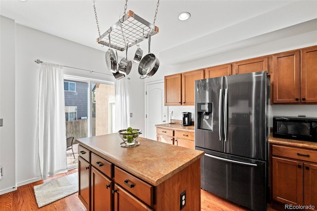 kitchen featuring stainless steel fridge with ice dispenser, a center island, and light hardwood / wood-style flooring