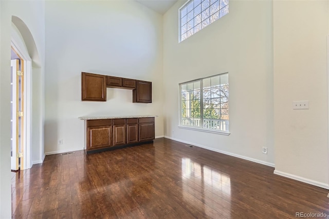 unfurnished living room featuring a high ceiling and dark wood-type flooring