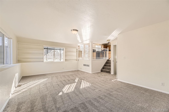 unfurnished living room featuring carpet floors and a textured ceiling