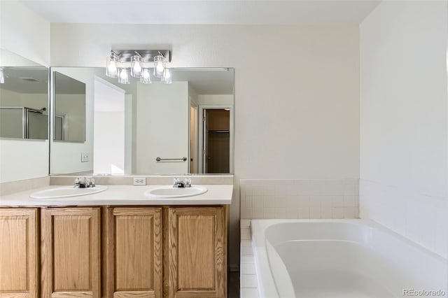 bathroom featuring tiled bath and vanity