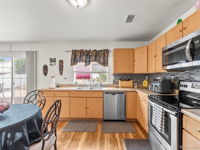 4906 Perth St, Denver, CO 80249 - kitchen featuring stainless steel appliances, light brown cabinets, light wood-style floors, light countertops, and a textured ceiling