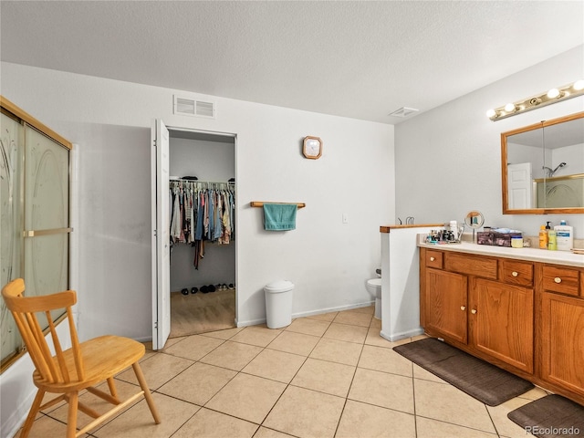4906 Perth St, Denver, CO 80249 - bathroom featuring vanity, tile patterned floors, a textured ceiling, a spacious closet, and a shower