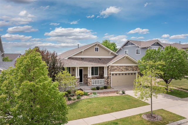 6520 S Newcastle Way, Aurora, CO 80016 - craftsman-style home featuring a porch, driveway, stone siding, a front lawn, and roof with shingles