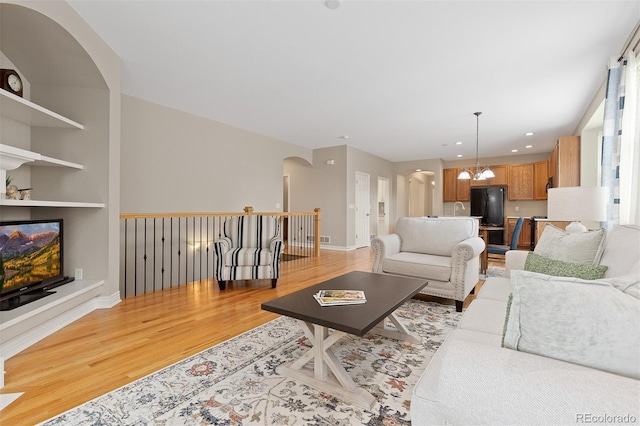 6520 S Newcastle Way, Aurora, CO 80016 - living area with light wood finished floors, arched walkways, baseboards, recessed lighting, and a chandelier