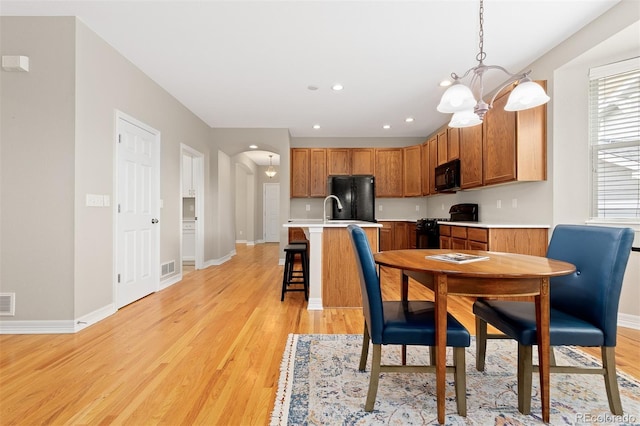 6520 S Newcastle Way, Aurora, CO 80016 - dining space with light wood-style flooring, arched walkways, a chandelier, recessed lighting, and baseboards