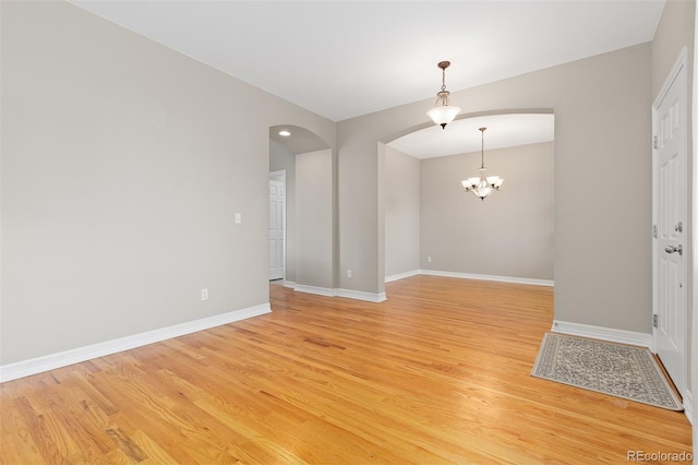 6520 S Newcastle Way, Aurora, CO 80016 - unfurnished room featuring arched walkways, light wood-style floors, a chandelier, and baseboards