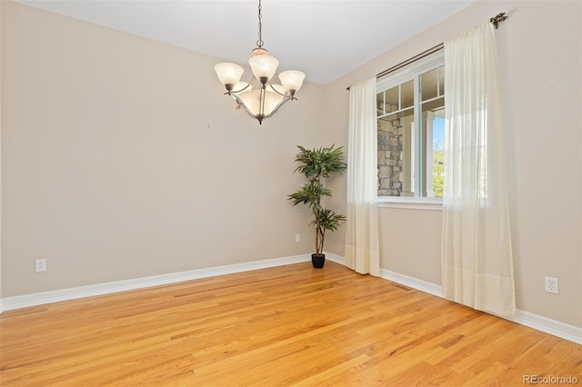 6520 S Newcastle Way, Aurora, CO 80016 - unfurnished room with a chandelier, light wood-style flooring, and baseboards
