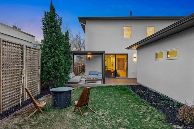 rear view of property with a yard, stucco siding, fence, and a patio