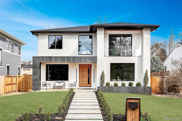contemporary house with stucco siding, fence, a front yard, and a balcony