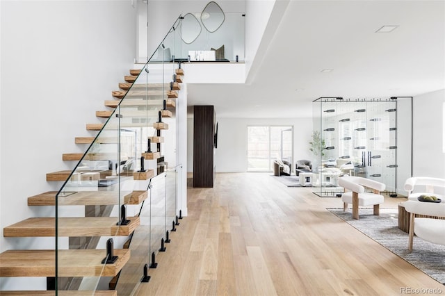 stairs with wood finished floors and a towering ceiling