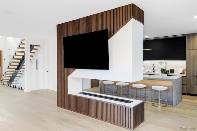 interior space with light wood-type flooring, indoor wet bar, and stairway