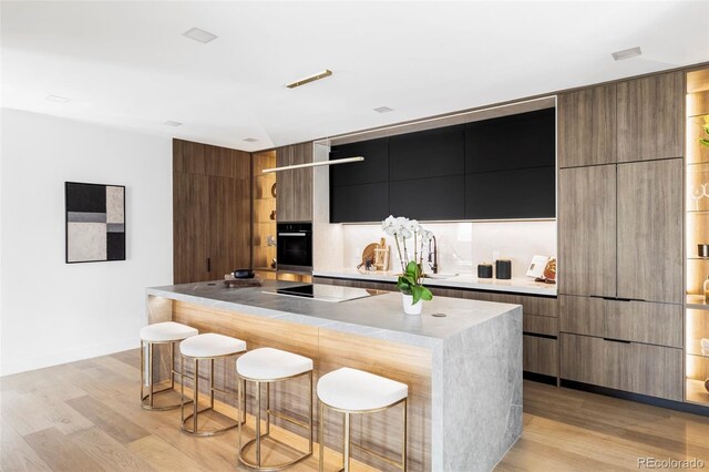 kitchen featuring a kitchen bar, modern cabinets, and black appliances