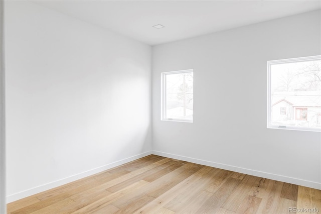 spare room with baseboards and light wood-type flooring
