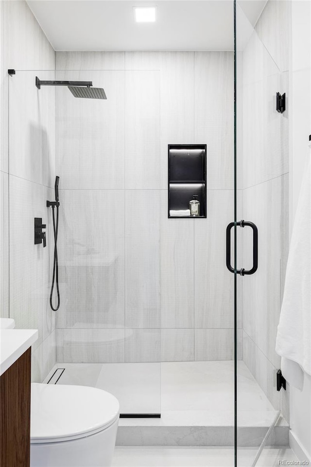 bathroom with toilet, vanity, and a shower stall