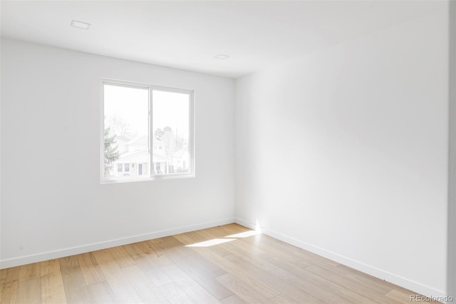 unfurnished room featuring baseboards and light wood-style floors