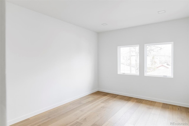 unfurnished room with baseboards and light wood-style floors