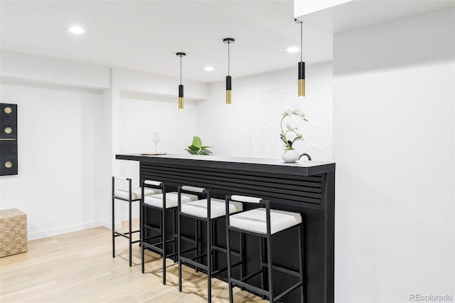 bar with decorative light fixtures, recessed lighting, baseboards, light wood-style flooring, and indoor wet bar