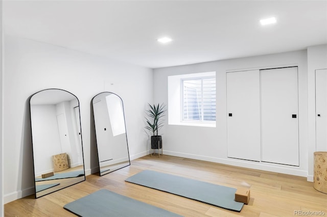 exercise area with baseboards and light wood-type flooring