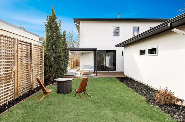 back of property featuring stucco siding, fence, and a lawn