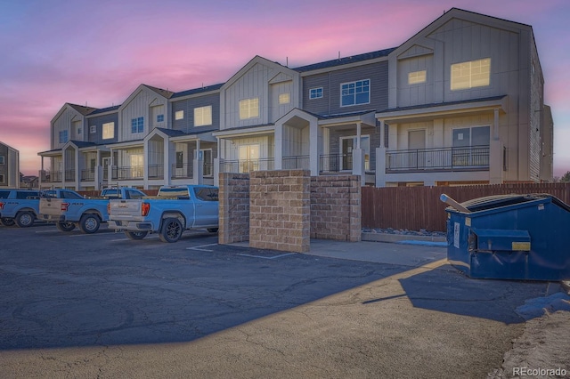 townhome / multi-family property with a residential view, fence, uncovered parking, and board and batten siding