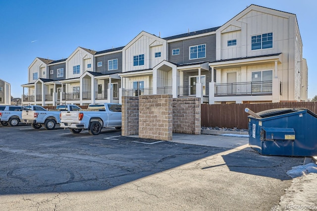 multi unit property featuring board and batten siding, a residential view, uncovered parking, and fence