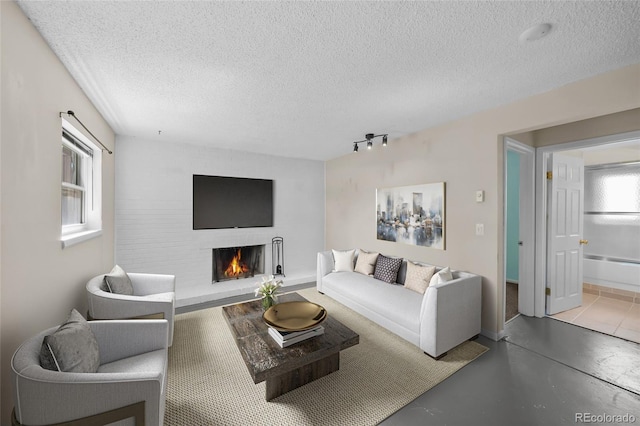 16563 E Kansas Pl, Aurora, CO 80017 - living room with a lit fireplace, a textured ceiling, track lighting, and concrete floors