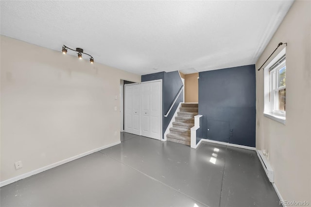 16563 E Kansas Pl, Aurora, CO 80017 - empty room featuring a baseboard heating unit, concrete flooring, stairs, and a textured ceiling