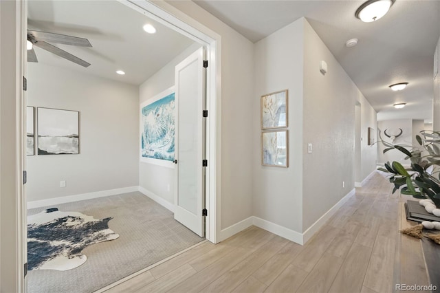 corridor with light wood-style floors, recessed lighting, and baseboards
