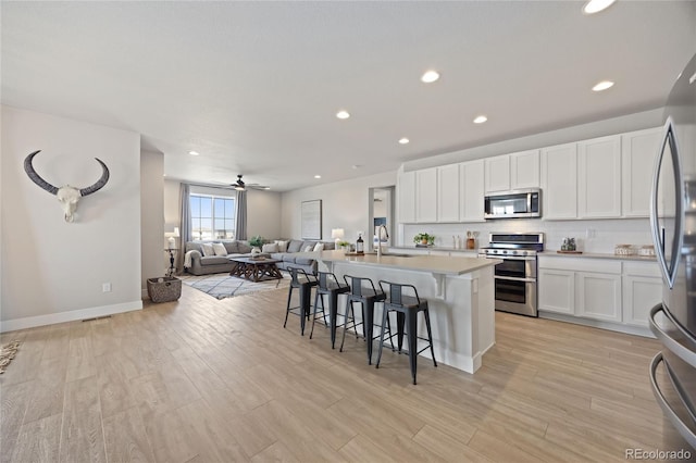 kitchen with a sink, a breakfast bar area, stainless steel appliances, open floor plan, and recessed lighting
