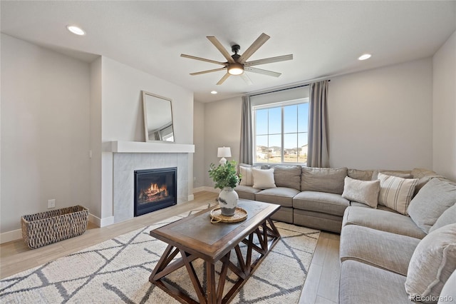 living area featuring a ceiling fan, recessed lighting, light wood finished floors, and a fireplace