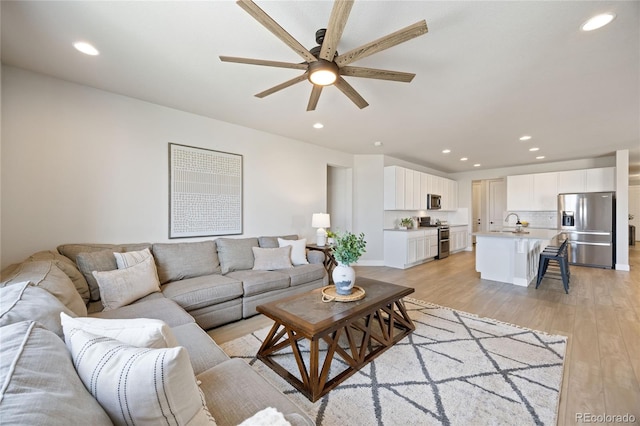 living room featuring light wood-style floors, a ceiling fan, and recessed lighting