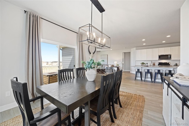 dining room with recessed lighting, light wood finished floors, baseboards, and a chandelier