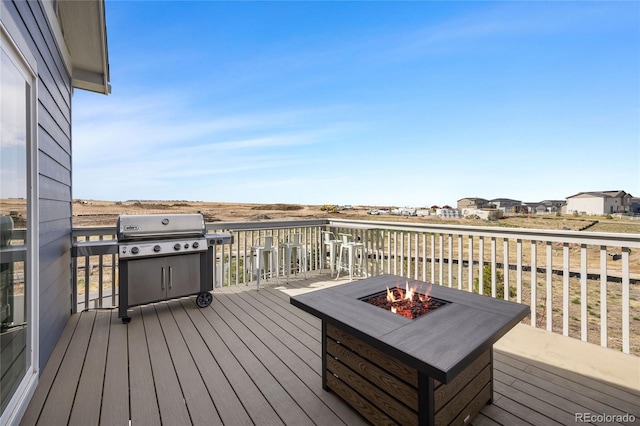 wooden terrace with an outdoor fire pit and grilling area